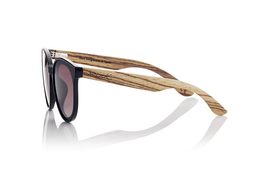 Gafas de Madera Natural de Walnut SOPHIA. Las gafas de sol Sophia son el accesorio perfecto para darle un toque de estilo a tus looks en todo tiempo. Con una montura redondeada en color negro satinado,  las lentes están montadas sobre la montura, lo que le da un toque retro y moderno al mismo tiempo. Las varillas anchas de madera de nogal veteada hacen un contraste armonioso con la montura. Este modelo es un modelo femenino muy atractivo aunque algunos hombres más atrevidos también querrán tener unas, está disponible en dos colores de lentes para que puedas elegir el que mejor se adapte a tus necesidades y estilo. No dudes en hacerte con unas gafas Sophia para proteger tus ojos del sol con estilo.Medida frontal aprox : 142x55mm Venta al Por Mayor y Detalle | Root Sunglasses® 